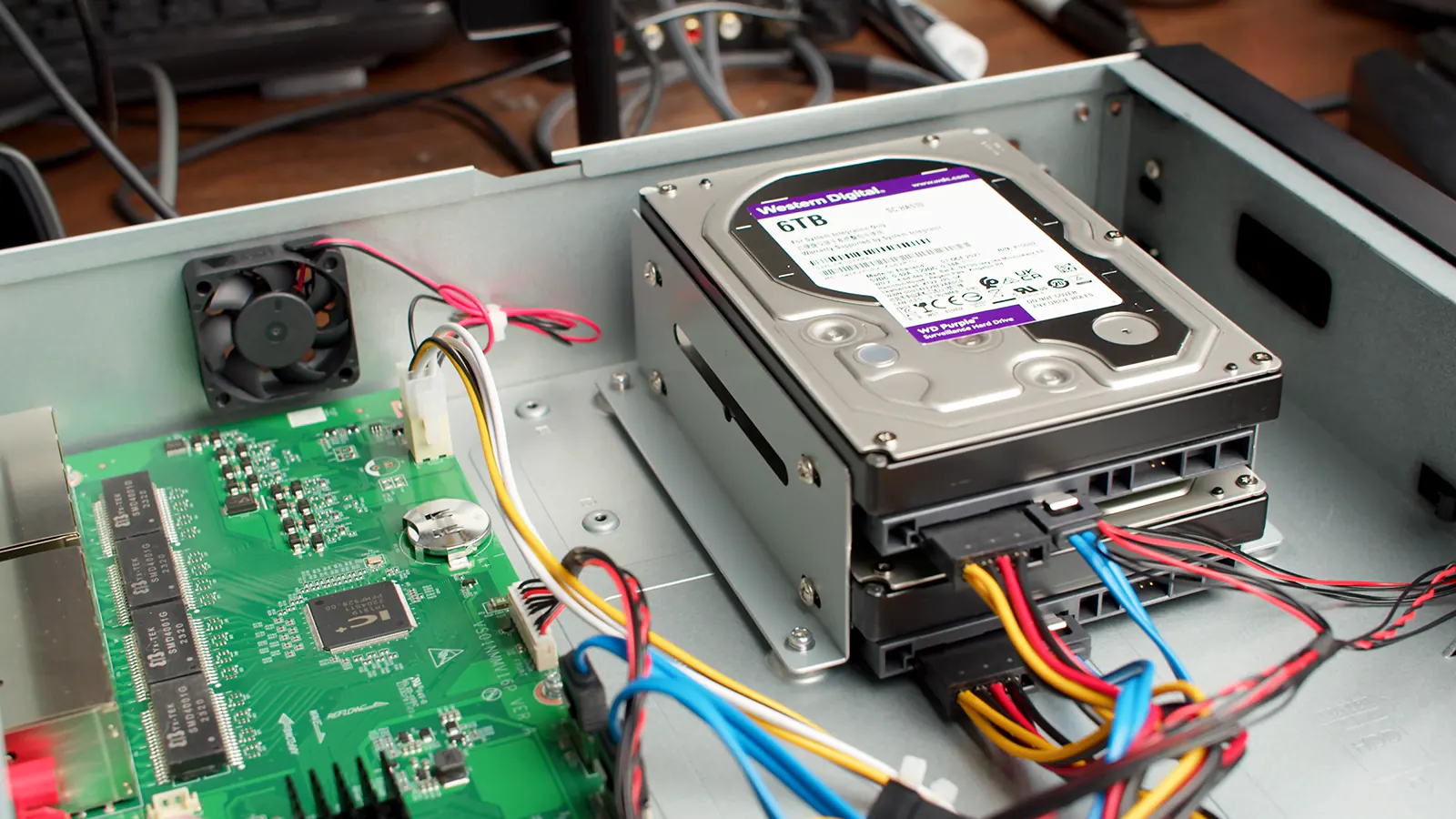 Two Western Digital 6TB Purple HDDs installed in an NVR, with SATA and power cables plugged into each drive.