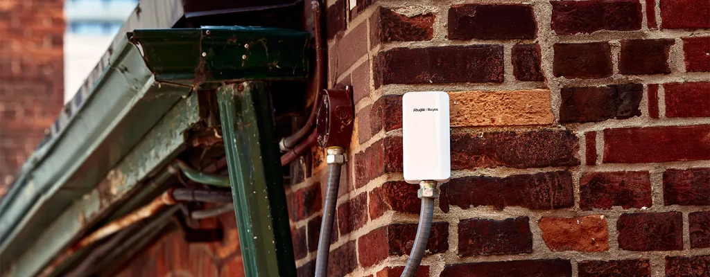 A white rectangular access point installed on a red brick building