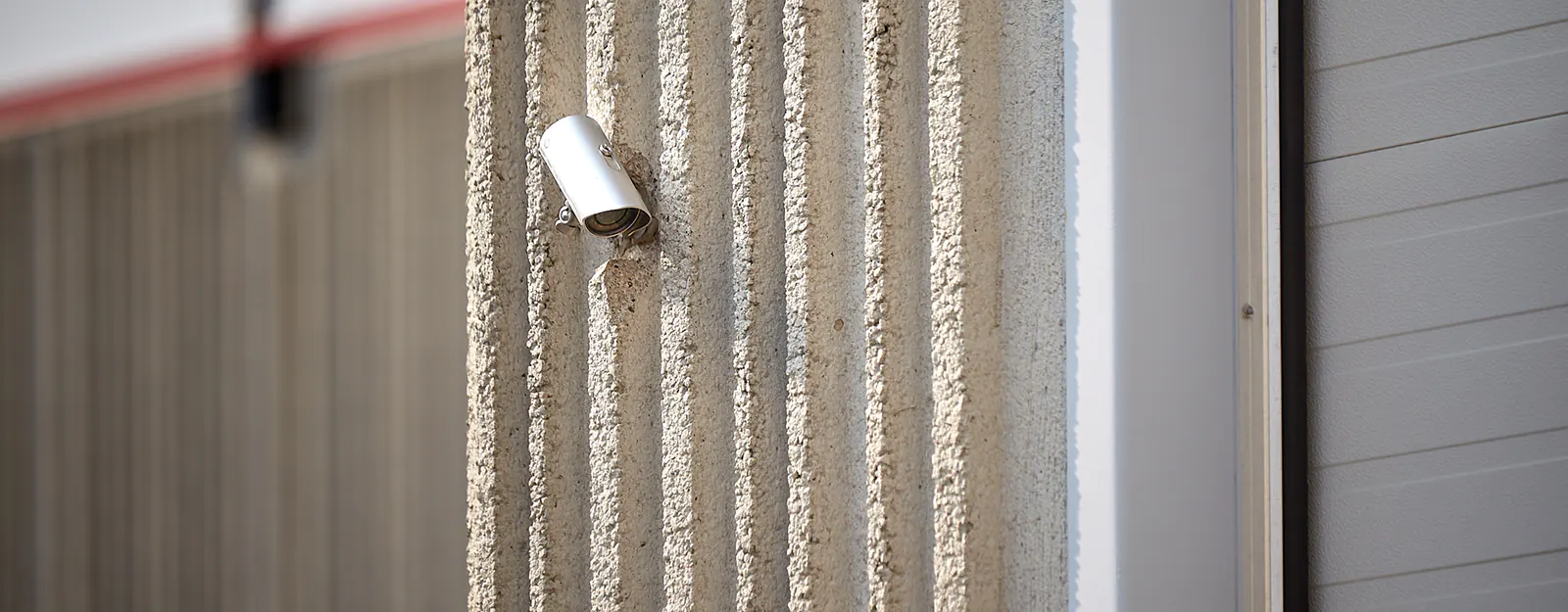 A metal bullet security camera watching a warehouse on a commercial building