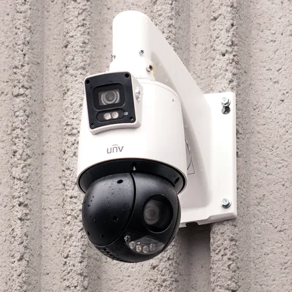 A large security camera mounted on a grey concrete wall, made by UNV